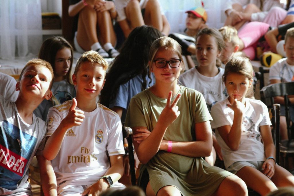 Cheerful group of children sitting together at an indoor event, showcasing friendships and diversity.