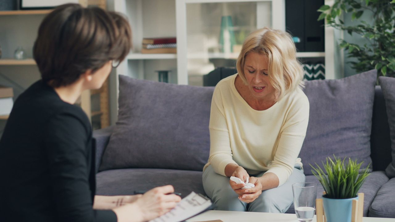A woman in therapy session with a professional therapist, expressing emotions.