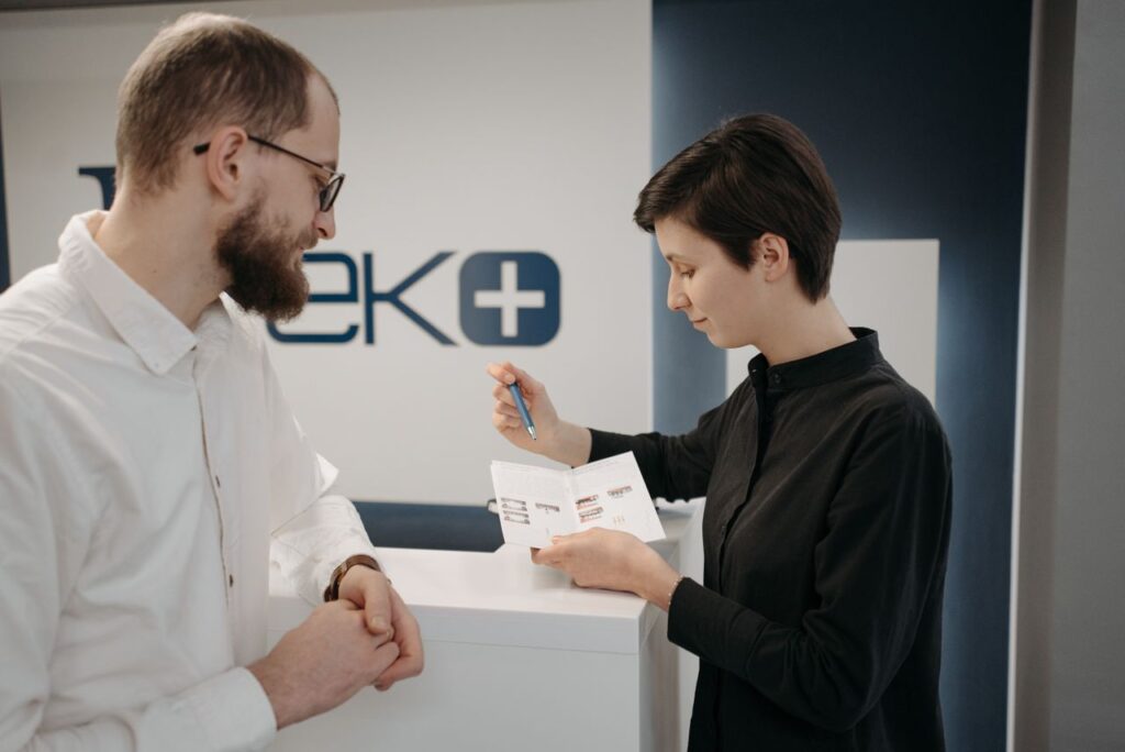 Customer discussing information sheet with receptionist in clinic.