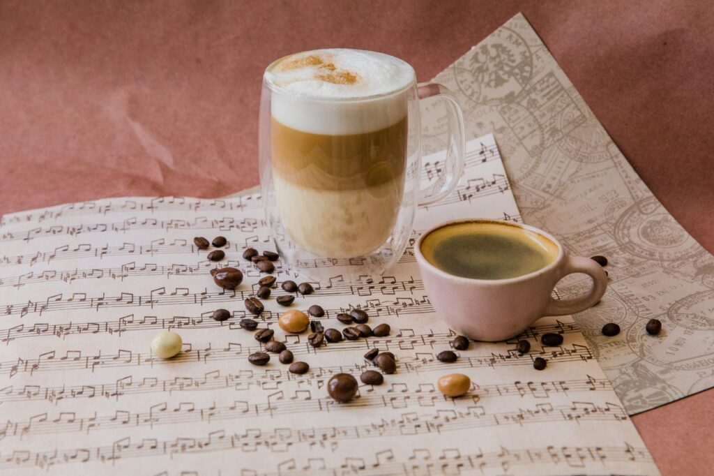 Cennik Aesthetic still life of coffee drinks with beans on sheet music backdrop, creating a cozy, creative scene.